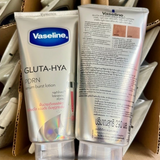 Two Vaseline Gluta-Hya PDRN serum burst lotion tubes, one showing the front packaging with a silver body and blue Vaseline logo, and the other showing the back packaging with extensive text in English and Thai, set against a background of shipping cardboard and other tubes.